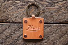 Russet handmade leather key fob with brass keyring and copper rivets on wood