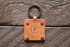 Russet handmade leather key fob with brass keyring and copper rivets on wood