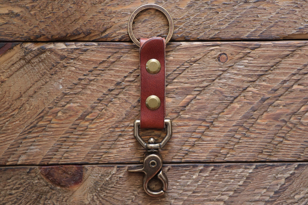 Brown handmade leather keychain with brass key ring and clip on wood